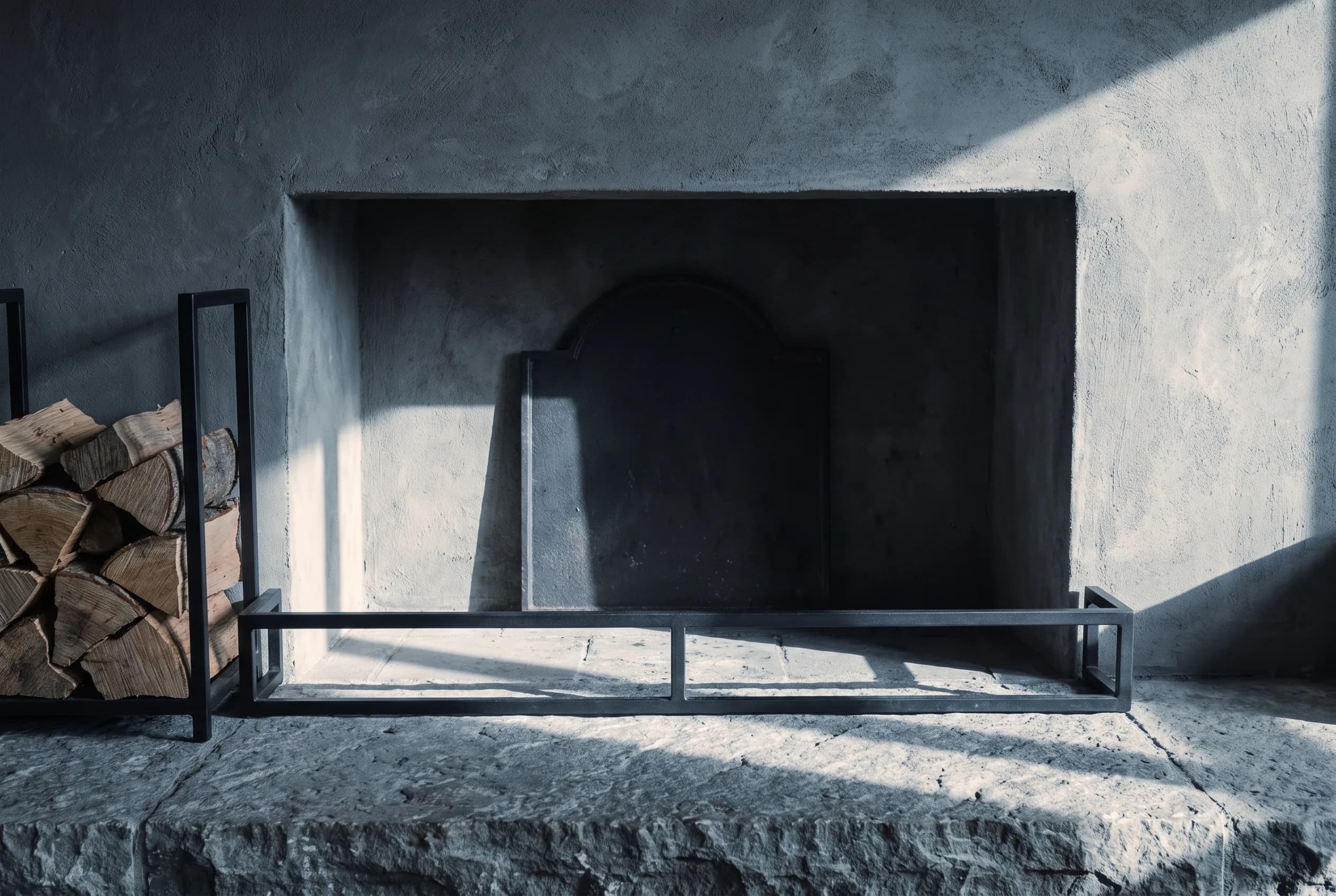 A cold fireplace with a hearth tool set standing beside it.